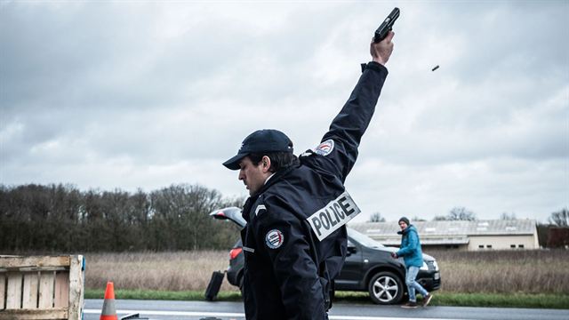Image de policier pointant une arme vers le ciel